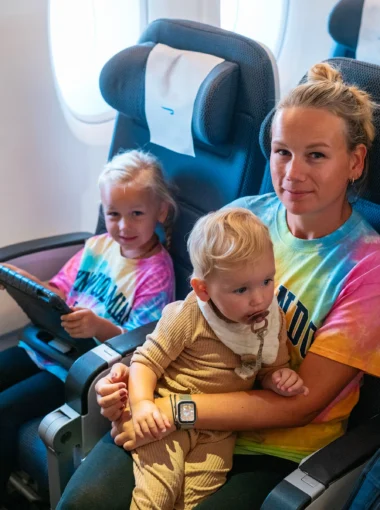 Moeder met twee jonge dochters in het vliegtuig op de terugweg van een rondreis door Florida, ontspannen genietend tijdens de vlucht.